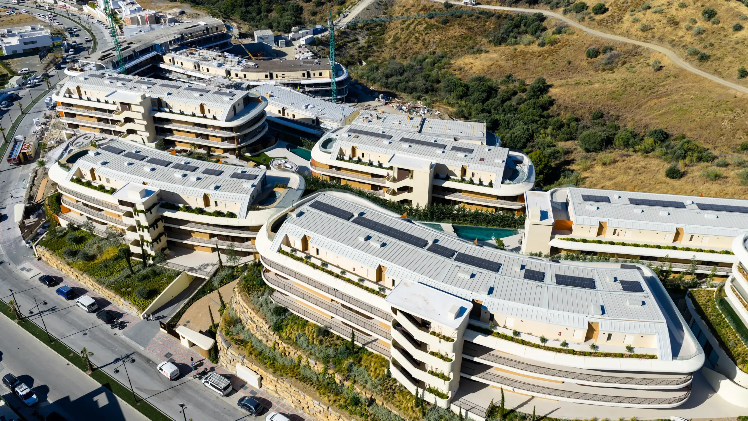 Vista aérea con dron de urbanización de lujo en Málaga con terrazas escalonadas, jardines y paneles solares en fachada