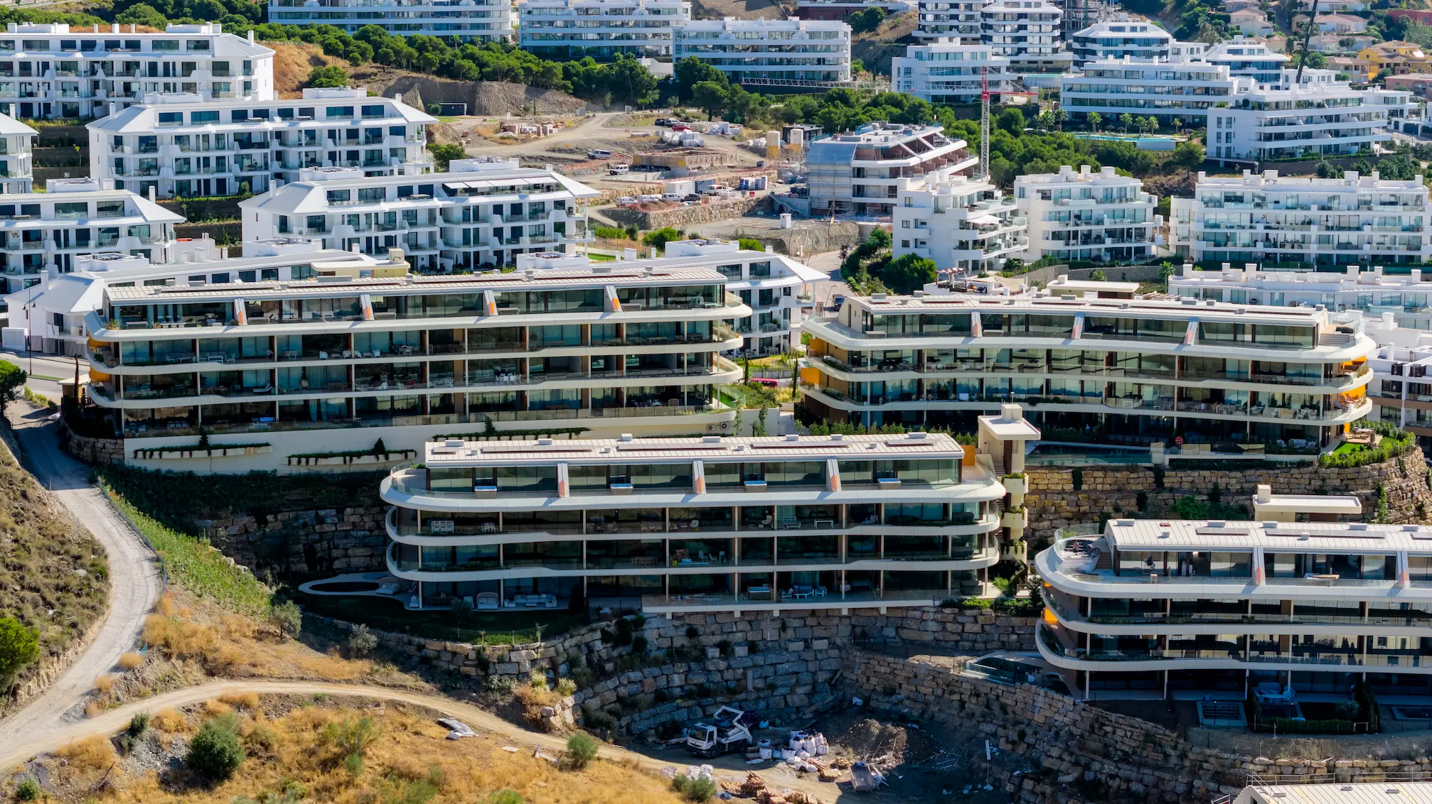Fotografía aérea de apartamentos de obra nueva con grandes terrazas acristaladas y diseño escalonado en ladera de Málaga