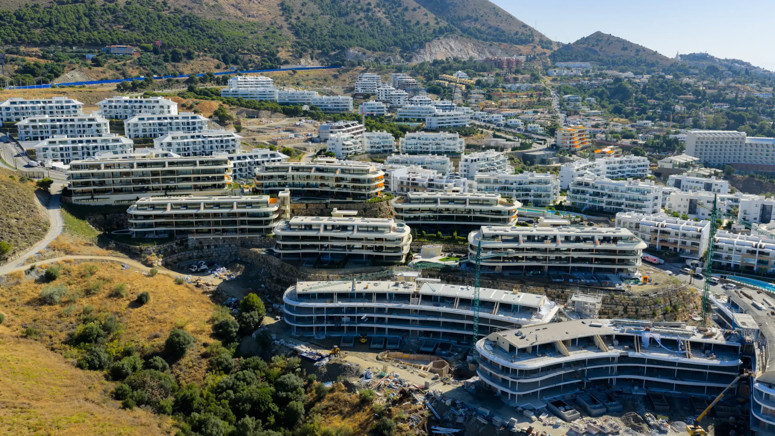 Fotografía aérea de promoción de obra nueva en construcción en Málaga con edificios de diseño curvo escalonados en ladera