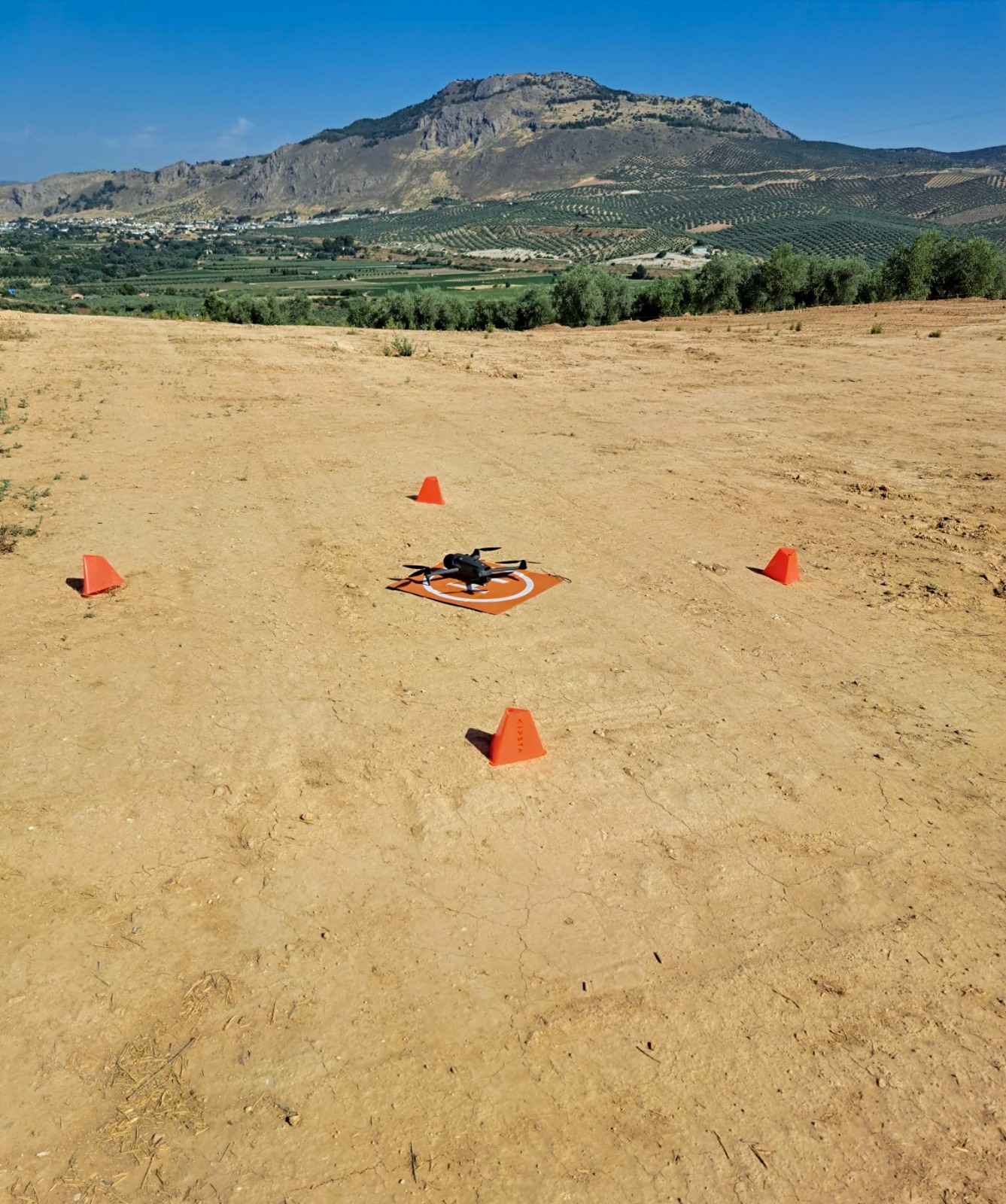 Dron profesional en plataforma de despegue señalizada con conos antes de un vuelo de seguimiento de obra
